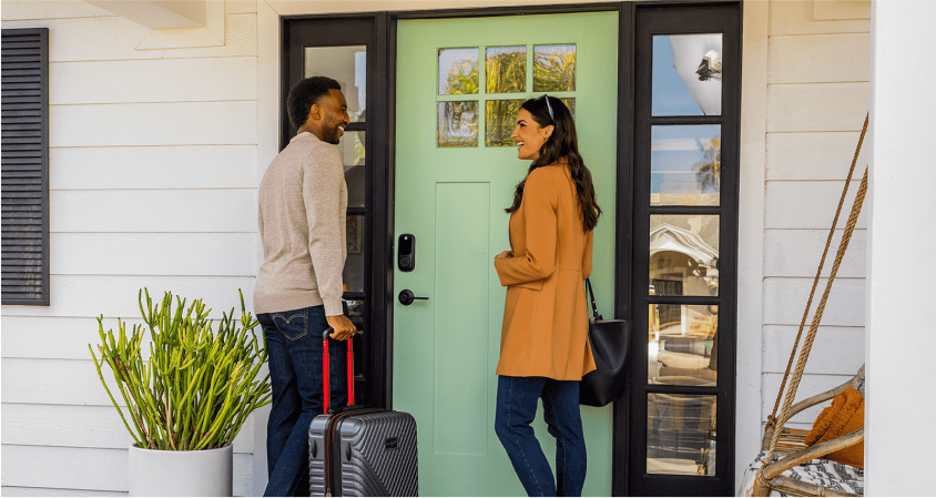 Couple at front door using smart lock for home entry.