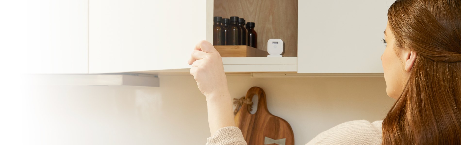 Woman using Smart Cabinet lock for cabinets that are compatible with samsung smart phone 